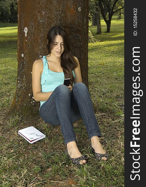 Young woman writing sms in park. Young woman writing sms in park