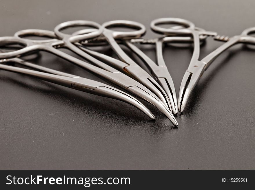 A set of arterial forceps on a dark background. A set of arterial forceps on a dark background.