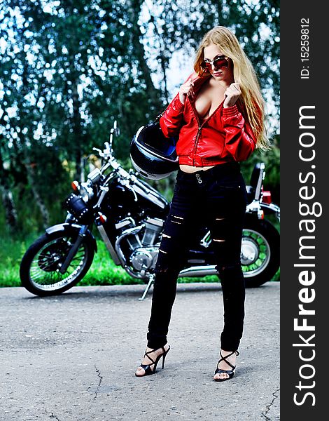 Shot of an attractive woman biker posing near her motorcycle. Shot of an attractive woman biker posing near her motorcycle.