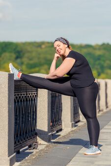 Young Woman Oversized Doing Stretching Exercises On The Embankment In A City Park In The Early Royalty Free Stock Images