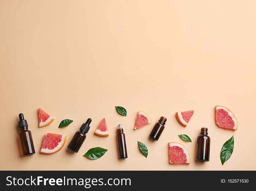 Flat lay composition with grapefruit slices and bottles of essential oil on color background