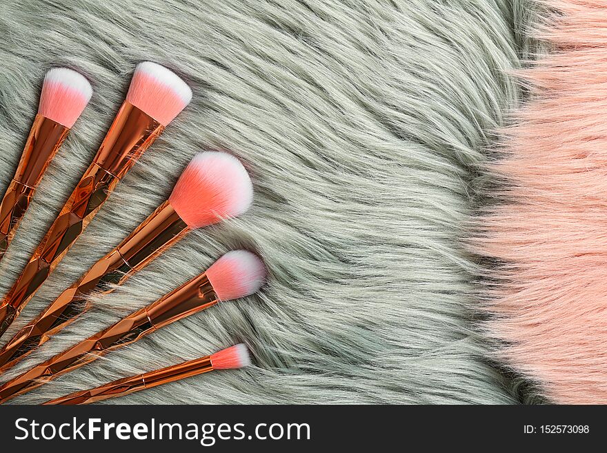 Set of professional makeup brushes on furry fabric, flat lay