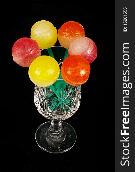 Colorful sweet lollipops in the glass on the black background