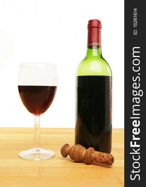 Glass and bottle of red wine with a stopper on wood