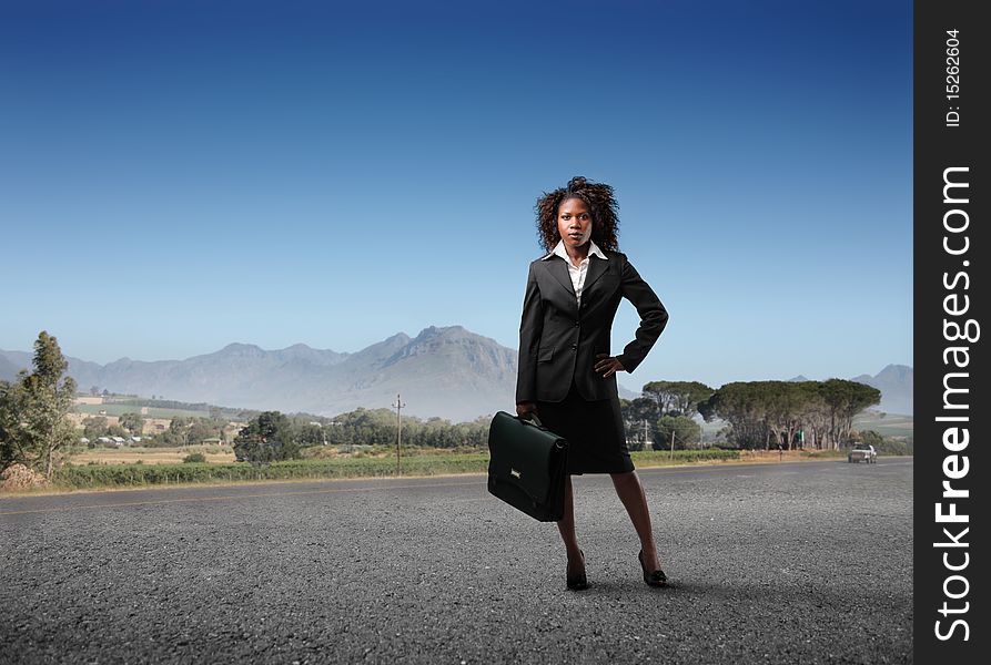 Black businesswoman standing on a countryside road. Black businesswoman standing on a countryside road