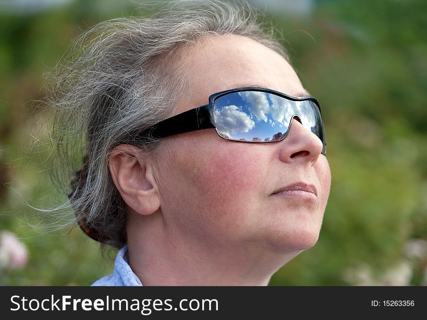 Mature Woman Looking Up To The Sky with Sunglasses