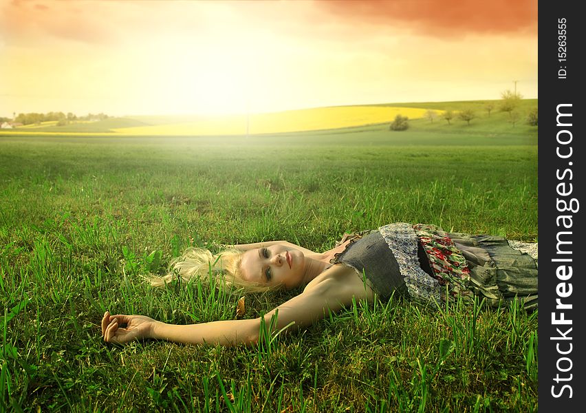 Beautiful woman lying on a gren meadow at sunset. Beautiful woman lying on a gren meadow at sunset