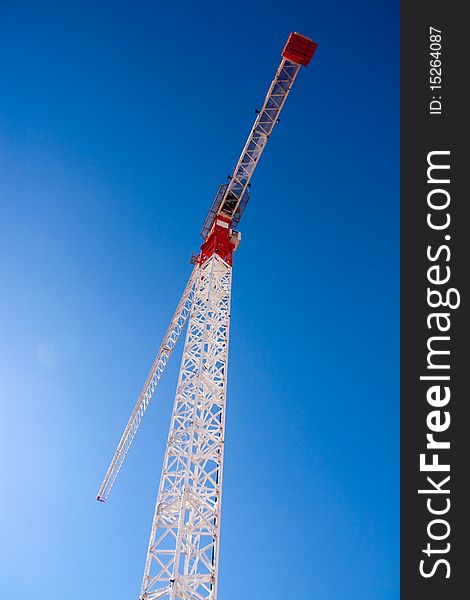 Crane towering overhead against blue sky. Crane towering overhead against blue sky.