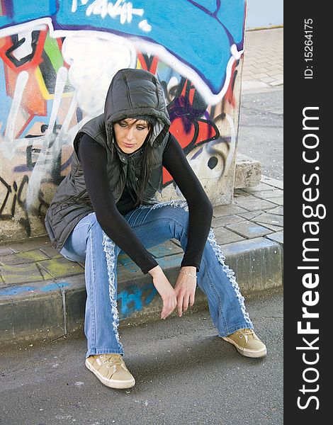 Pensive / upset woman / girl sitting on a sidewalk, wearing winter clothing, in an urban setting. Pensive / upset woman / girl sitting on a sidewalk, wearing winter clothing, in an urban setting.