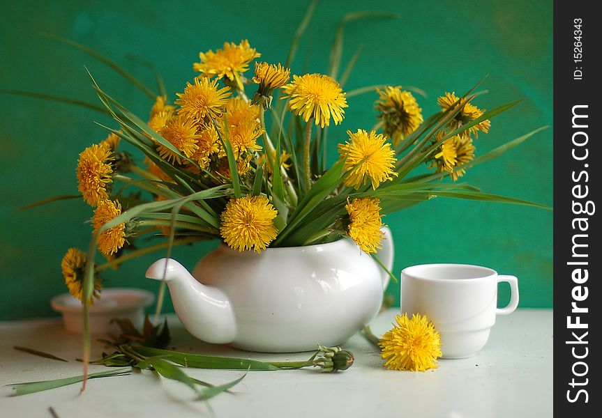 the bouquet of dandelions is costed in a tea-pot. the bouquet of dandelions is costed in a tea-pot