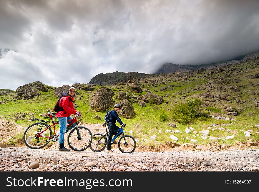 Two cyclists biking in mountains