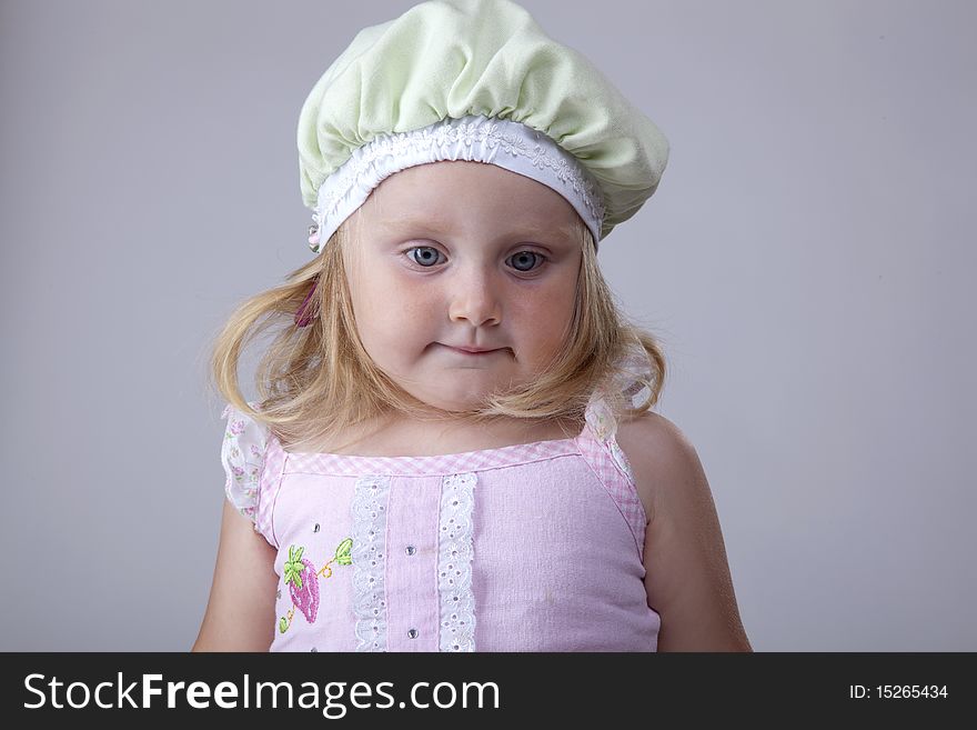 Blonde little girl looking innocent with a green hat