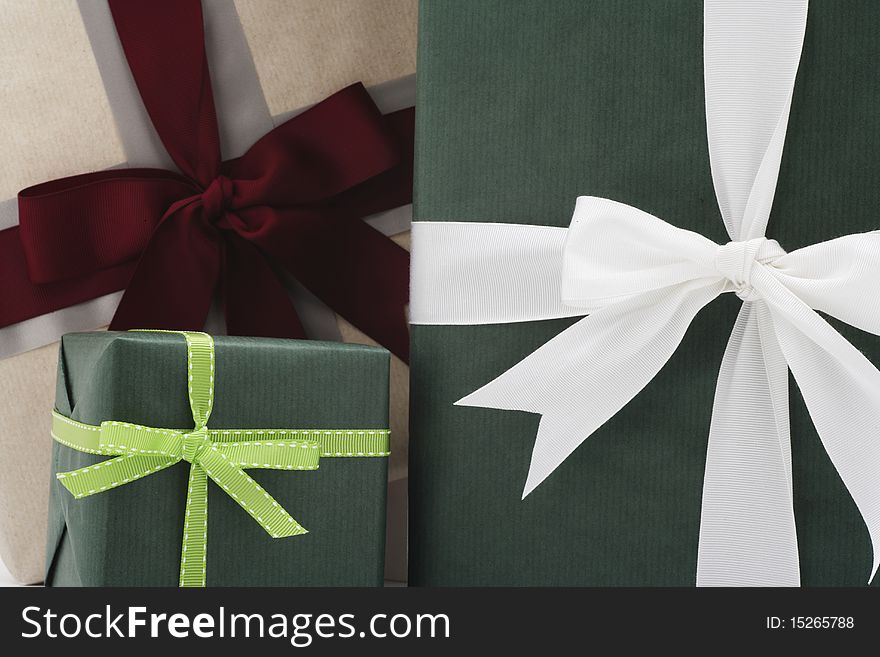 Three presents in front of each other in three different sizes.  Two are wrapped in green paper and the other is wrapped in beige. Three presents in front of each other in three different sizes.  Two are wrapped in green paper and the other is wrapped in beige.