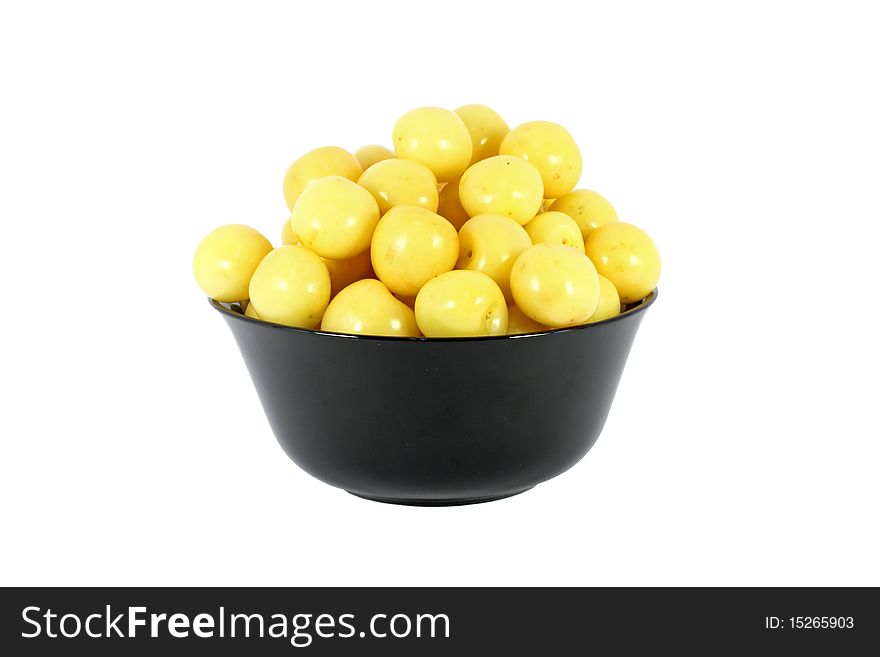 Black bowl full of yellow cherries isolated on white
