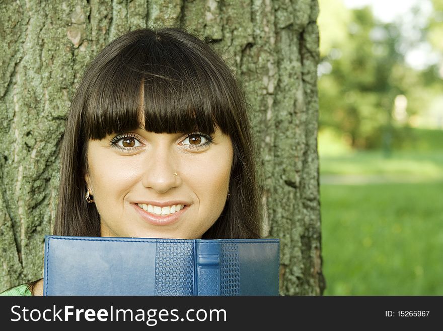 Young beautiful woman in a park with a notebook. Young beautiful woman in a park with a notebook