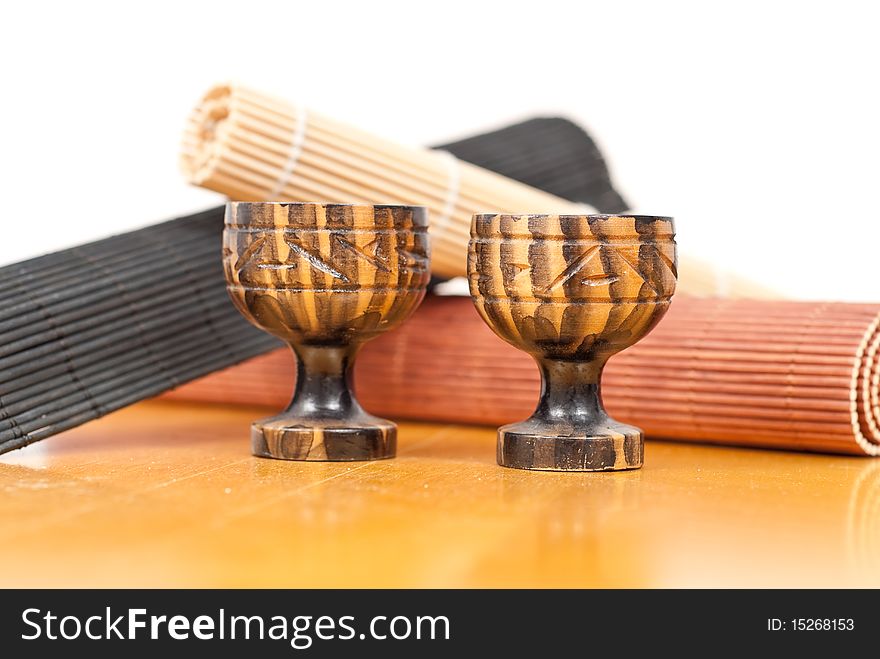 Two Mini Saki Tea Cups In Front Of Bamboo Mat Rolls. Two Mini Saki Tea Cups In Front Of Bamboo Mat Rolls