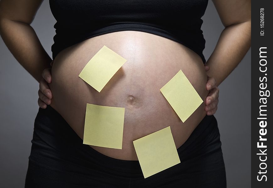 Pregnant woman with blank sticky notes on her belly. Pregnant woman with blank sticky notes on her belly.