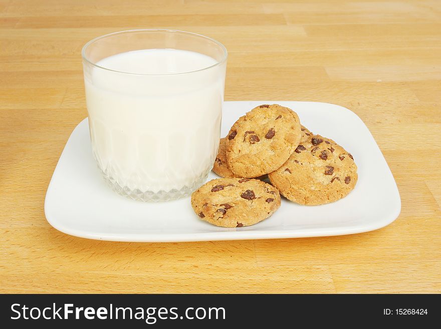 Glass of milk and chocolate chip cookies on a wooden worktop