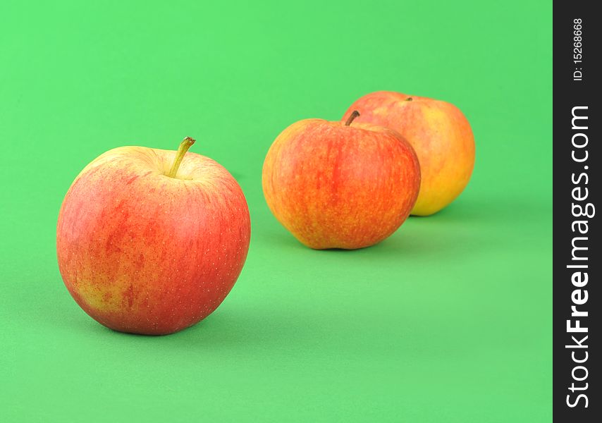 Three ripe by apples isolated over green background