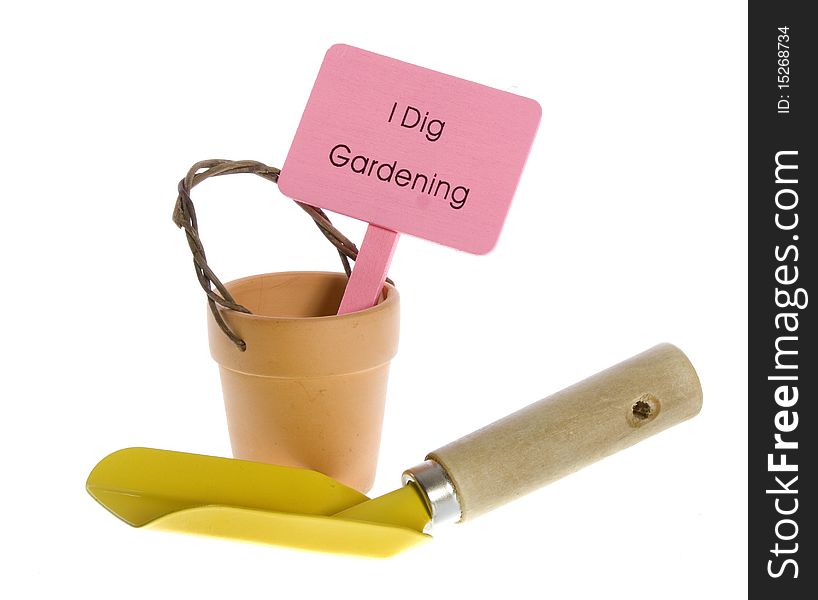 Empty orange clay terra cotta pot with pink sign that says I Dig Gardening, with yellow trowel in front of it. isolated on white. Empty orange clay terra cotta pot with pink sign that says I Dig Gardening, with yellow trowel in front of it. isolated on white.