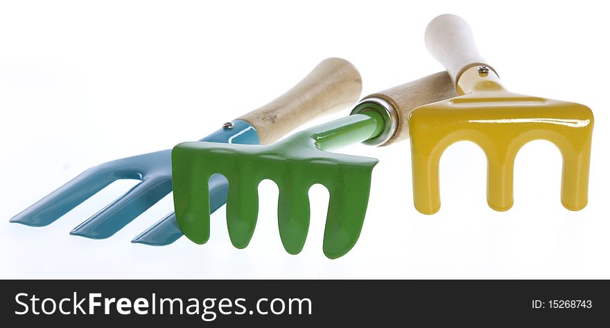 Three Colorful Hand Garden Tools: blue pitchfork, green hand rake, and yellow fork used for small gardens, isolated on white.