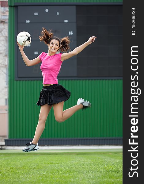 Girl cheerleaders jumping with a soccer ball