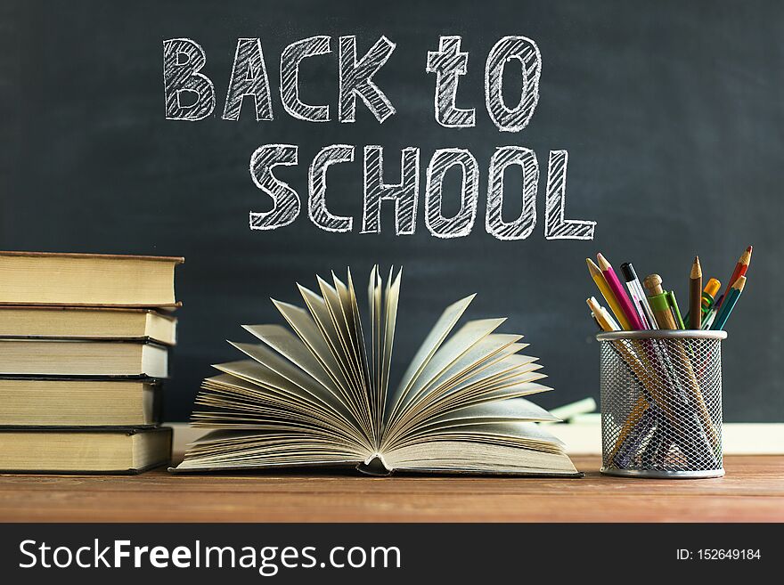 Textbooks And School Supplies On A Table, Against A Chalkboard Background With Chalk. Concept Of School With Copyspase