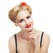 Blonde Girl Style Pin-up In Black Dress And Pearl Necklace Looks Playfully At Camera And Gently Touching Face With Your Stock Photo