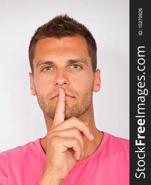 Young man holding finger over mouth gesturing silence. Young man holding finger over mouth gesturing silence