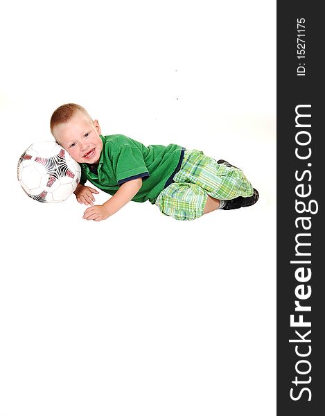 A toddler boy lying on a football in his green outfit, looking into the camera on white background. A toddler boy lying on a football in his green outfit, looking into the camera on white background.