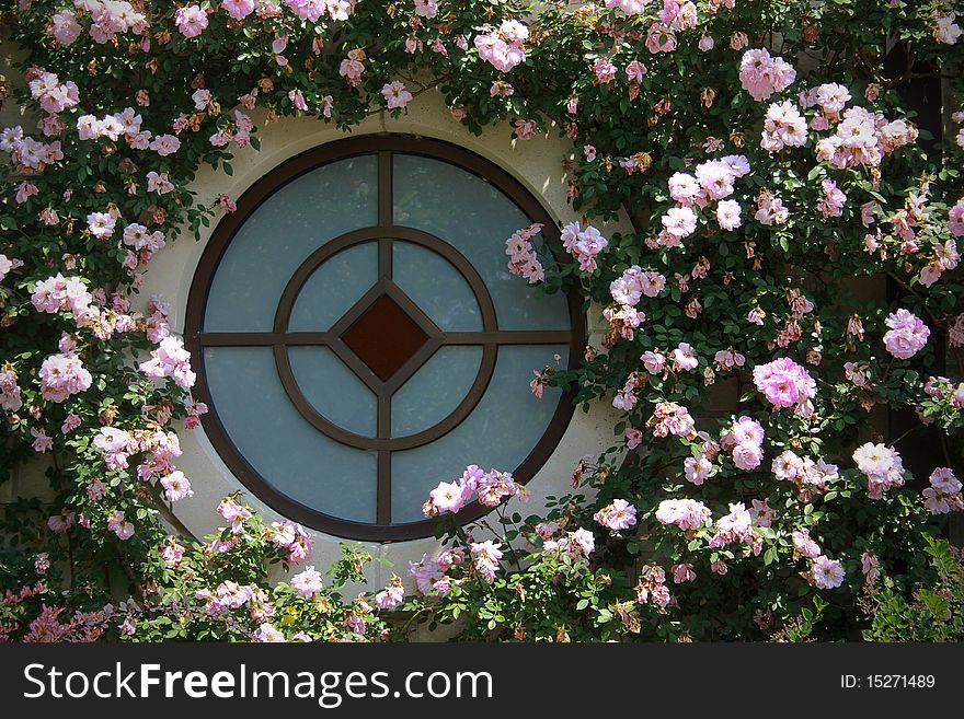 Unique round window surrounded by pink flowers. Unique round window surrounded by pink flowers.