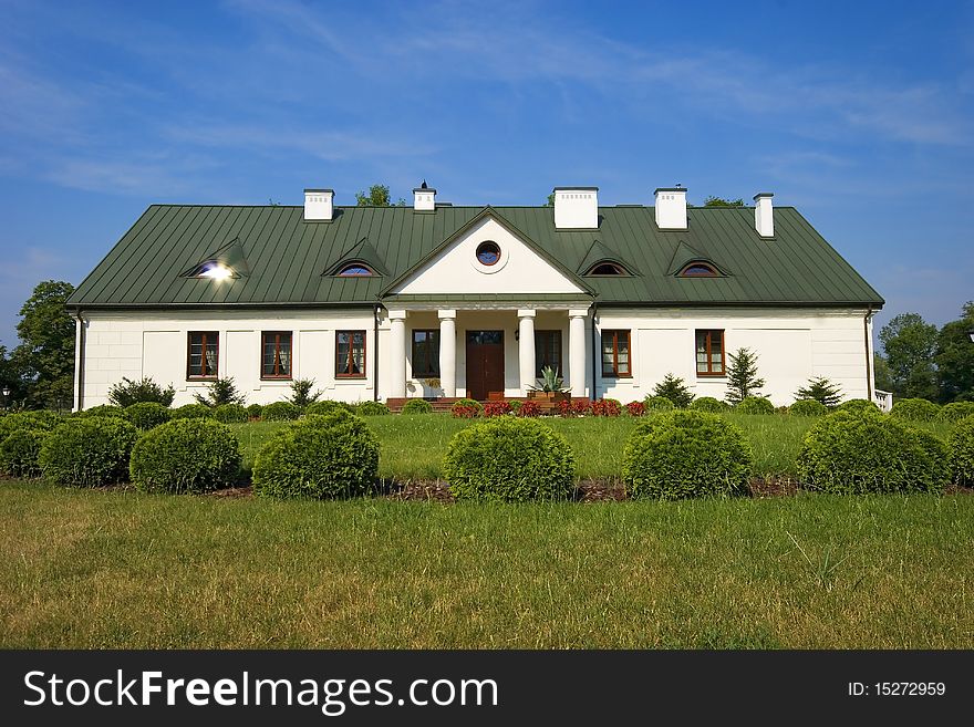 Country small manor house with the garden with the blue sky