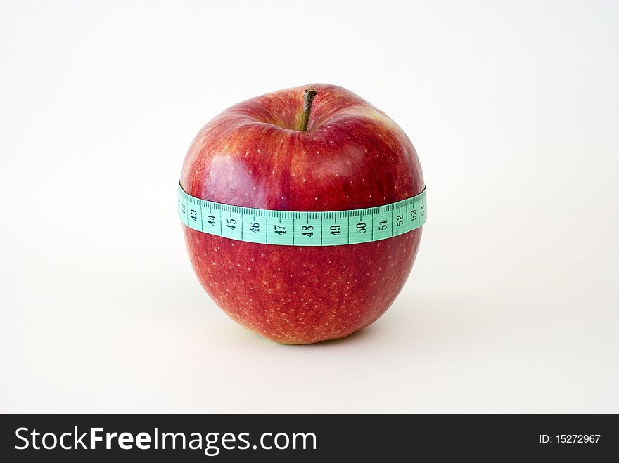 Fresh red apple wrapped up with the tape measure on the white background