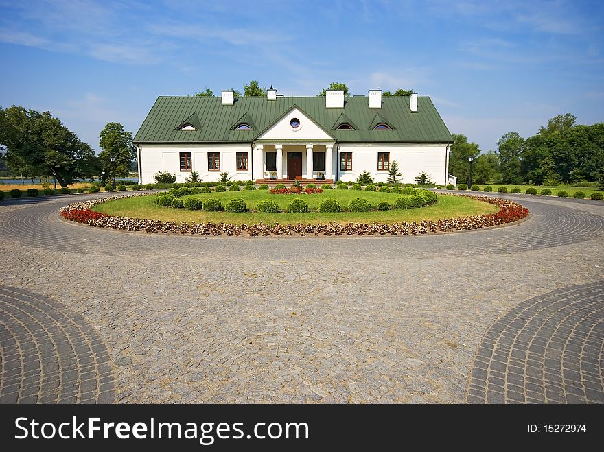 Country small manor house with the garden with the blue sky