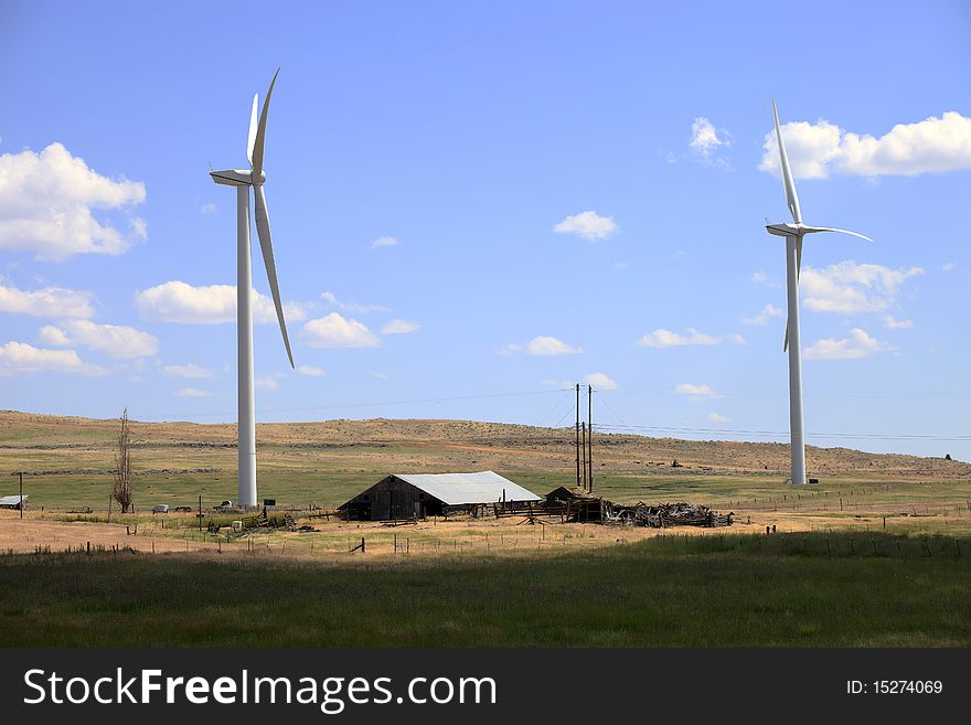 Two wind turbines stand between and old and abandoned shack in a farmland, eastern Washington state. Two wind turbines stand between and old and abandoned shack in a farmland, eastern Washington state.