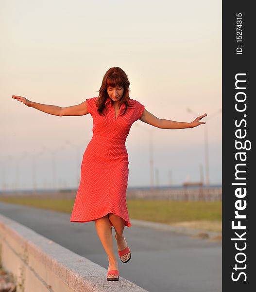 Girl walking along the stone fence in the evening. Girl walking along the stone fence in the evening