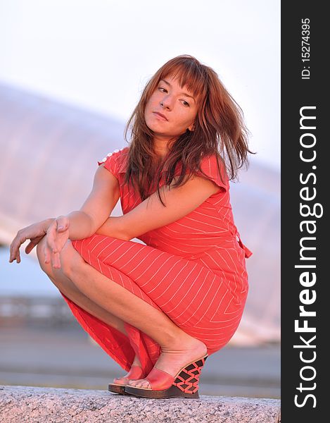 Pensive woman sitting outdoors; warm lighting setup; right hand is slightly out of focus. Pensive woman sitting outdoors; warm lighting setup; right hand is slightly out of focus