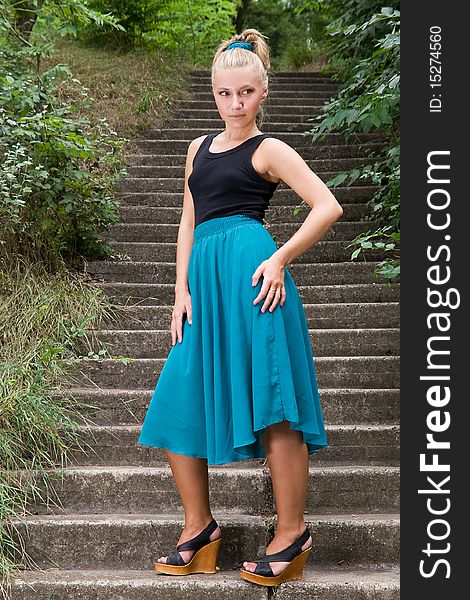 Beautiful young lady standing on old staircase somewhere in green park. Beautiful young lady standing on old staircase somewhere in green park