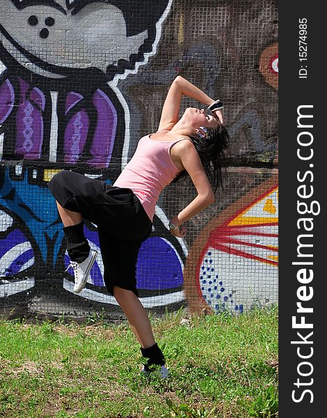 Woman modern ballet dancer in city against graffiti wall