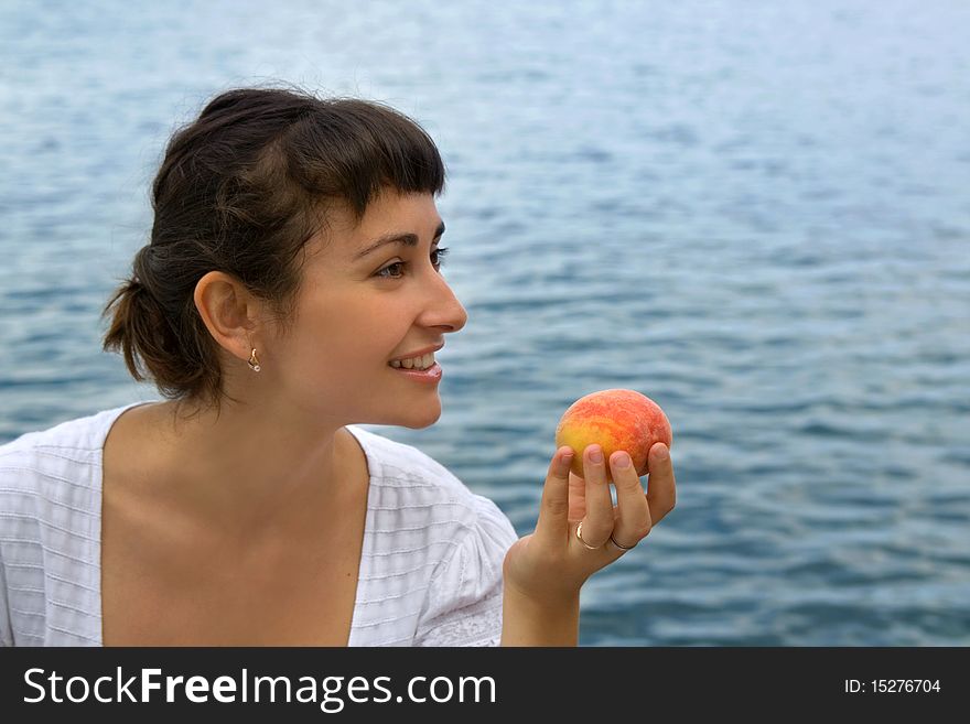 Young girl with the peach near the sea