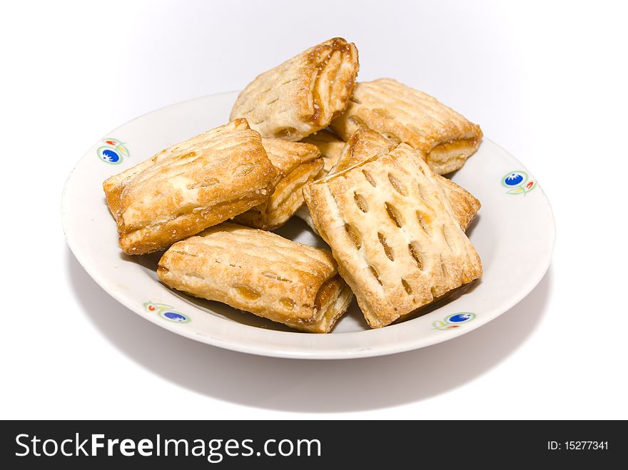 Sweet fresh pies with filling, lying heaped on a plate on a white background. Sweet fresh pies with filling, lying heaped on a plate on a white background