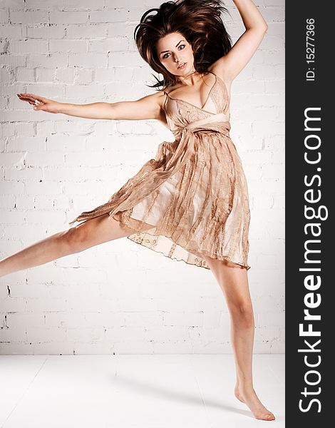 A young brunette model doing a crazy dance in a pretty dress.