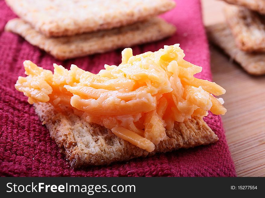 Wheat crackers on a kitchen board with grated garlick cheese. Wheat crackers on a kitchen board with grated garlick cheese.