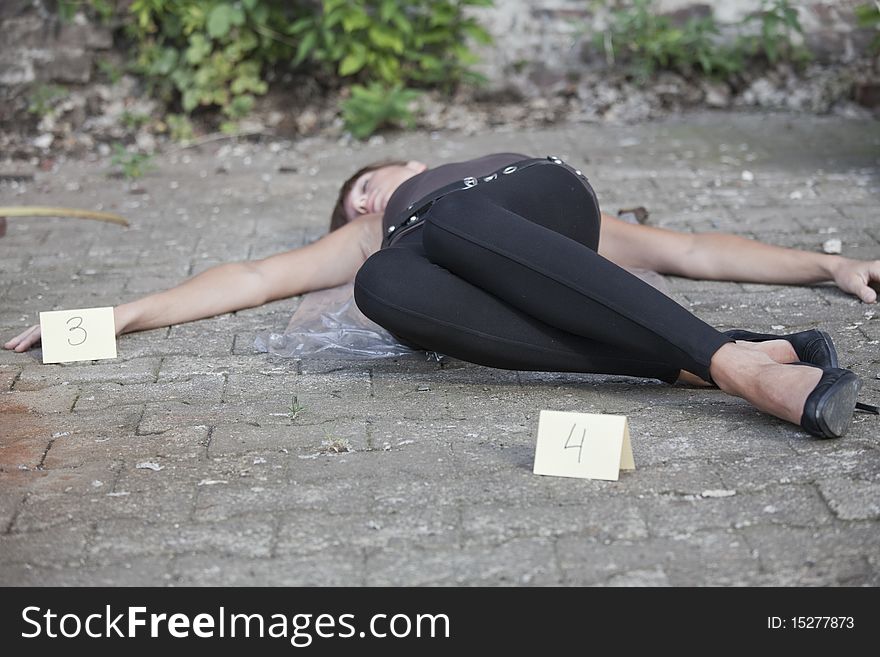 Crime scene - young woman lying on a ground with two placards at the sides