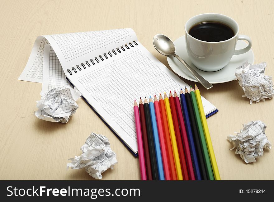 Coffee cup and spiral notebook and pen on the wooden table