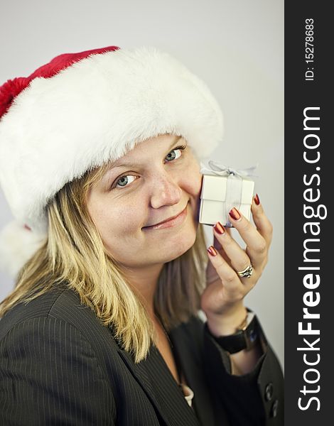 Young business woman wearing a santa hat holding christmas gift. Young business woman wearing a santa hat holding christmas gift