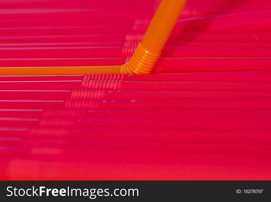 Many straws side by side, focus on the single orange straw