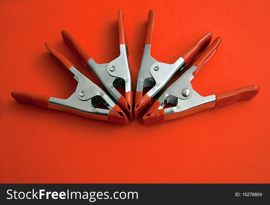 4 clamps on a red structured paper. 4 clamps on a red structured paper