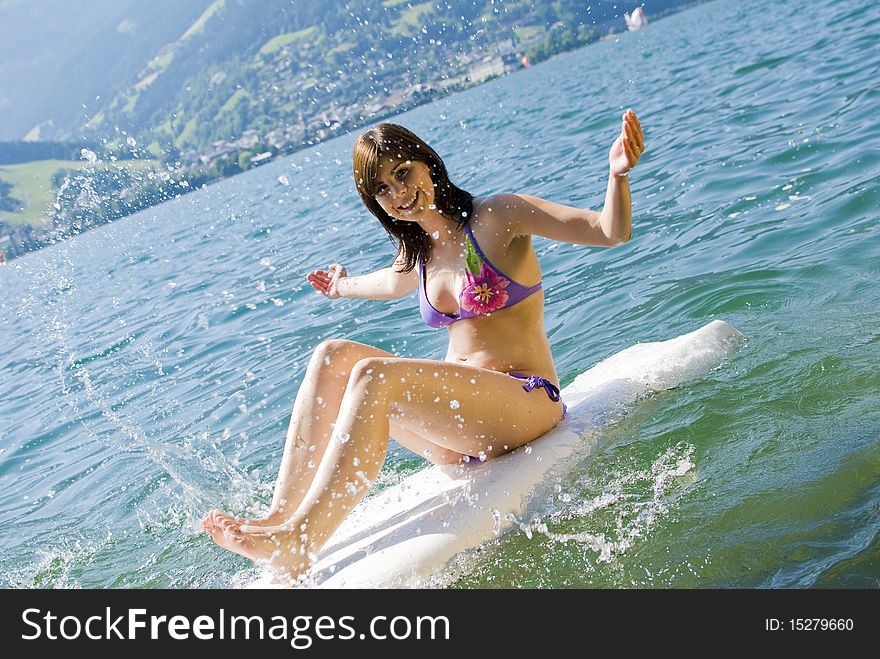 Girl having fun and relaxing on surfboard at the lake of Zell am See, Austria. Girl having fun and relaxing on surfboard at the lake of Zell am See, Austria