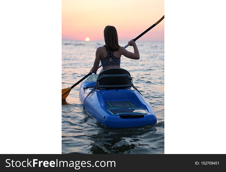 Young girl on the kayak greets the dawn of the sun